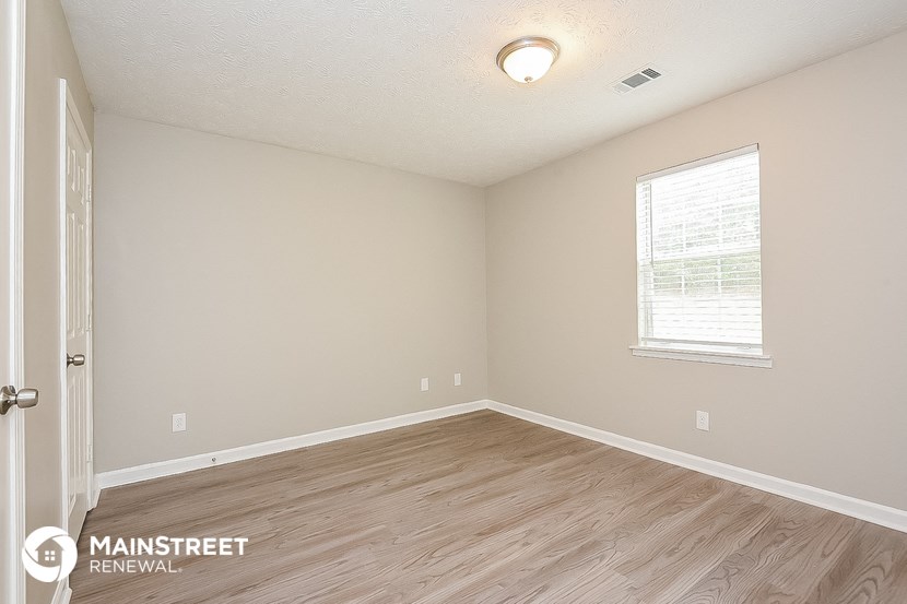 the spacious living room with wood flooring and a window