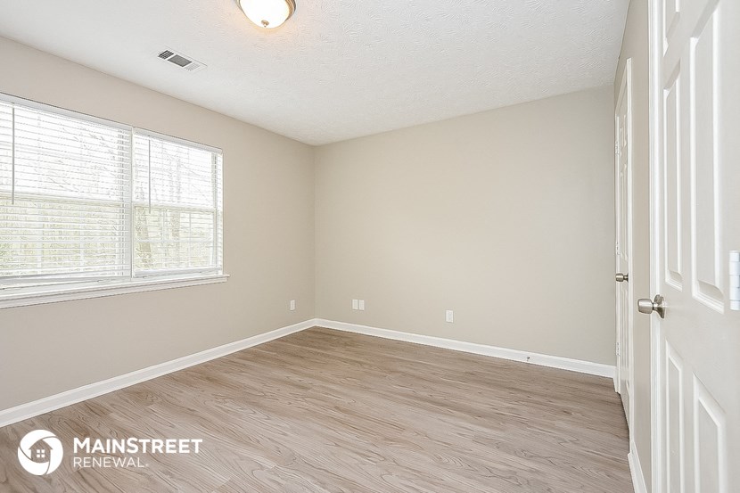 the spacious living room with wood floors and a large window