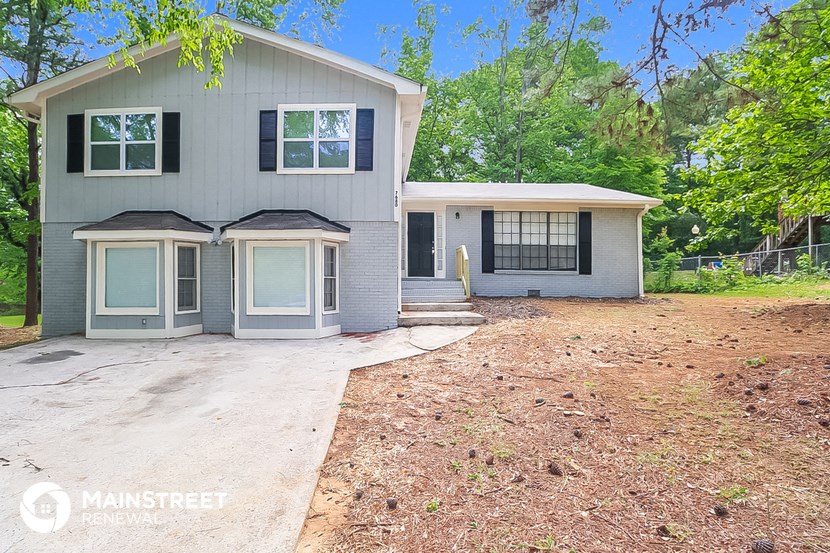 a blue and white house with a driveway and trees