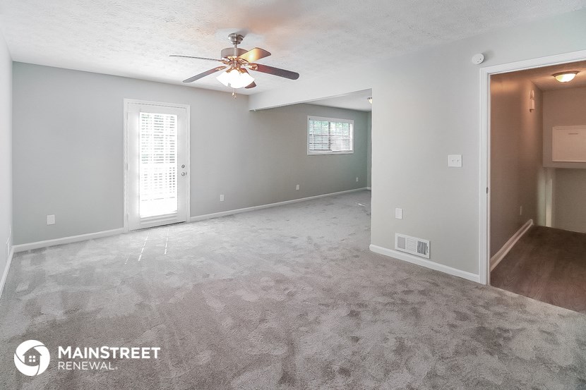 the living room and dining room of an empty house with a ceiling fan