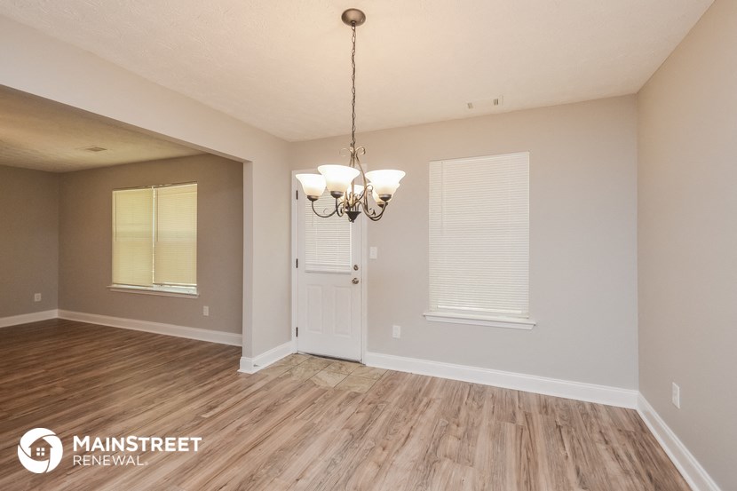 the living room and dining room with wood flooring and a chandelier