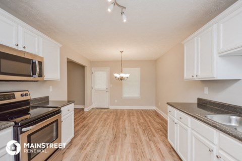 the kitchen and dining room of an apartment with white cabinets and stainless steel appliances