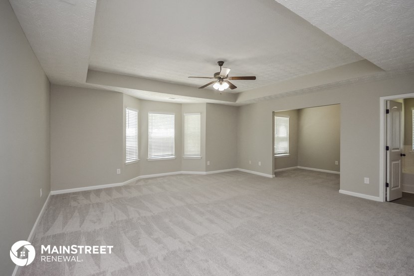 an empty living room with a ceiling fan