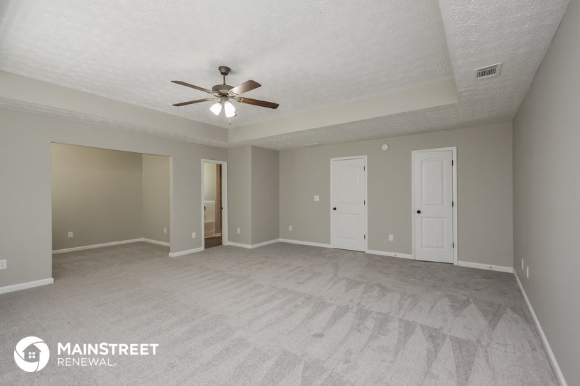 an empty living room with a ceiling fan
