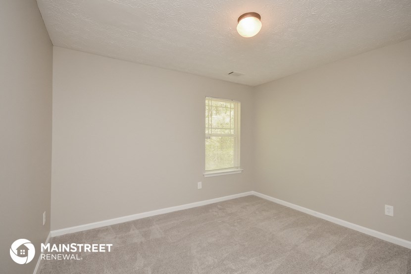 the interior of an empty room with carpet and a window