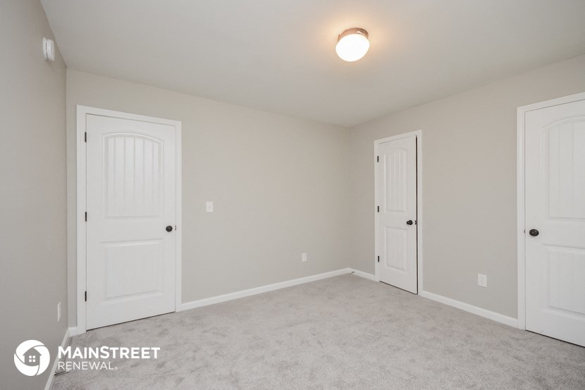 a bedroom with two doors and a carpeted floor and two closets