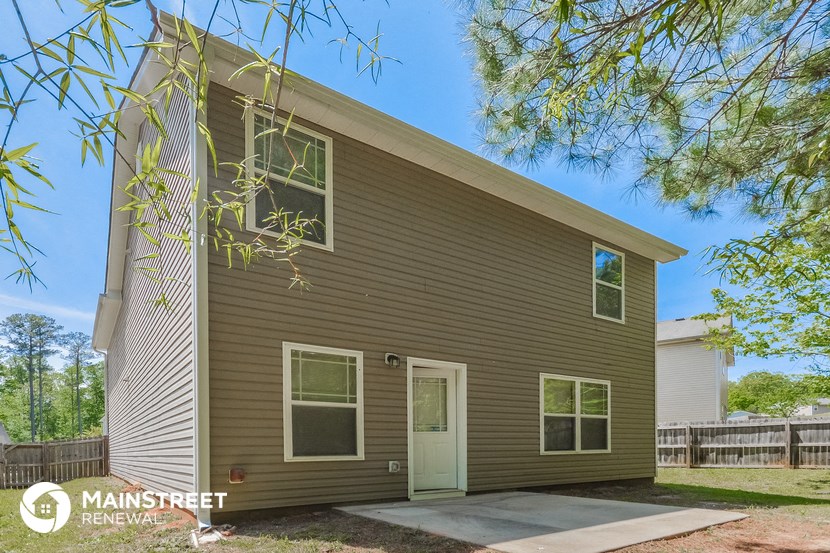 a small house with a green door and a tree in front of it