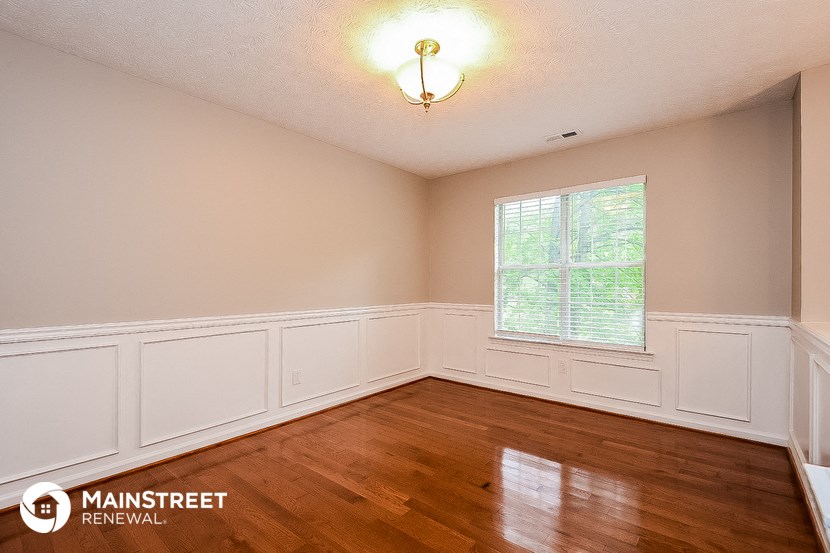 the living room of a home with wood floors and white walls