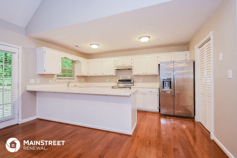 a kitchen with white cabinets and a stainless steel refrigerator