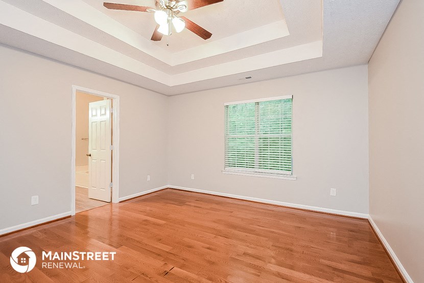 the living room of a home with wood floors and a ceiling fan
