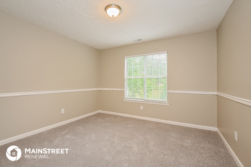 the bedroom of a rental home with carpet and a window
