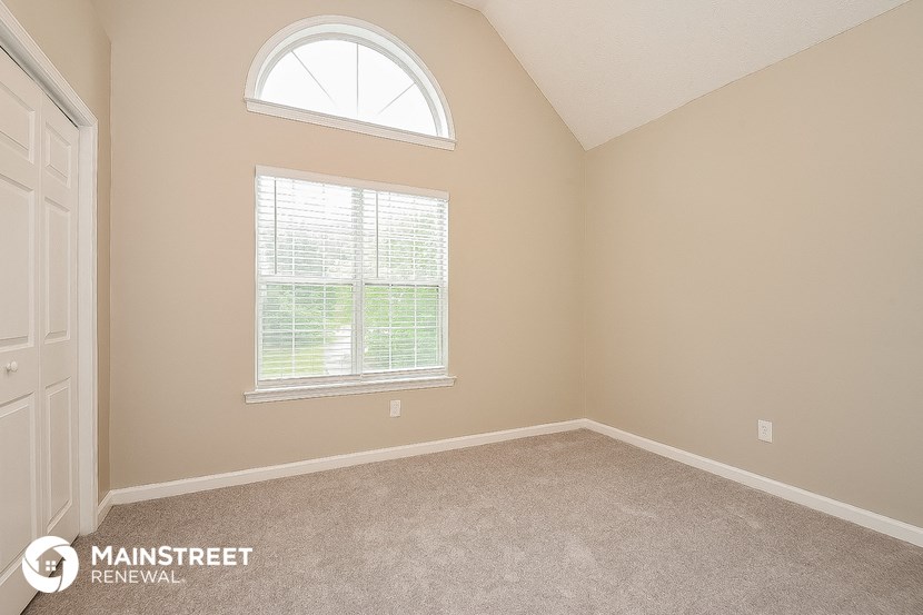 the bedroom of a home with a large window and carpet