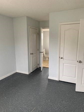an empty room with white doors and a door to a bathroom