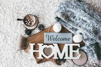 a sign that reads welcome home with a blanket and a cup of coffee