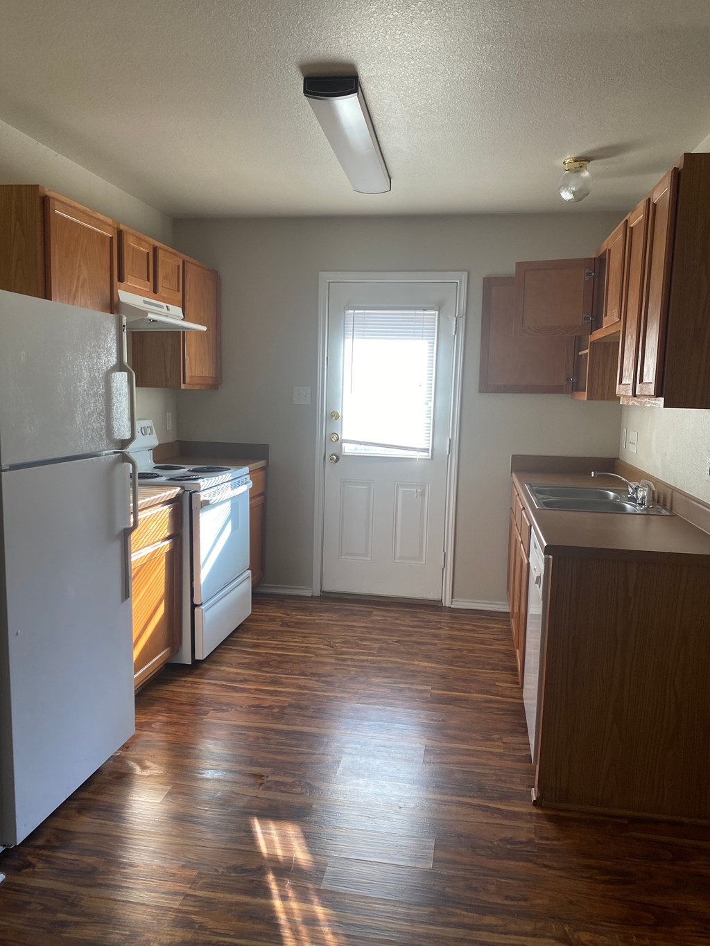 A kitchen with wooden floors and white appliances.