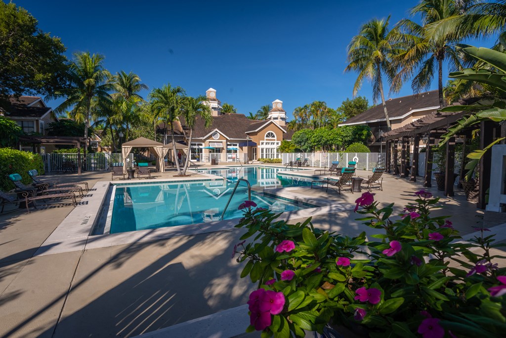 a swimming pool with palm trees and tables and chairs around it