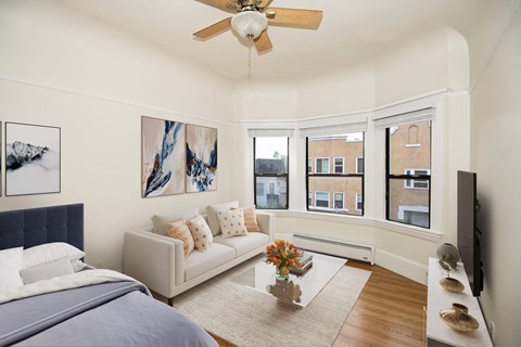 A bedroom with a bed, couch, and artwork on the wall.