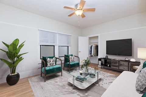A living room with a ceiling fan, two chairs, a sofa, and a television.