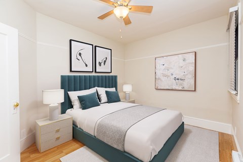 A bedroom with a bed, nightstand, and two framed pictures on the wall.
