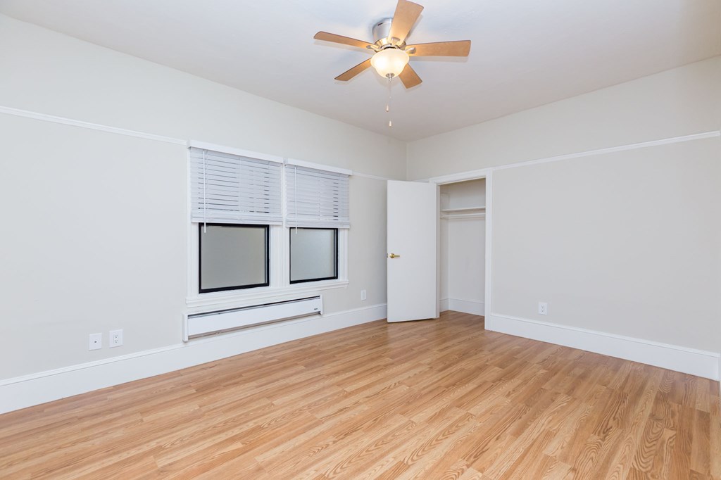 an empty living room with a ceiling fan and window