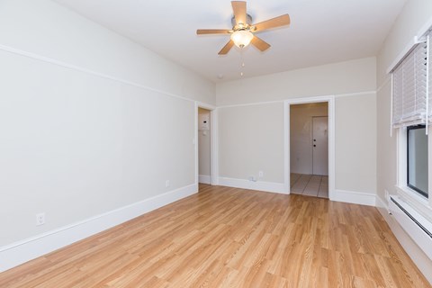 A room with a ceiling fan and wooden flooring.