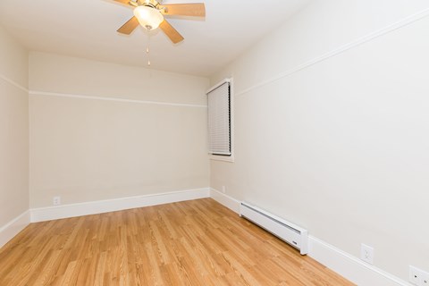 A room with a ceiling fan and wooden flooring.