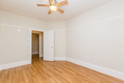 A room with a ceiling fan and wooden floors.