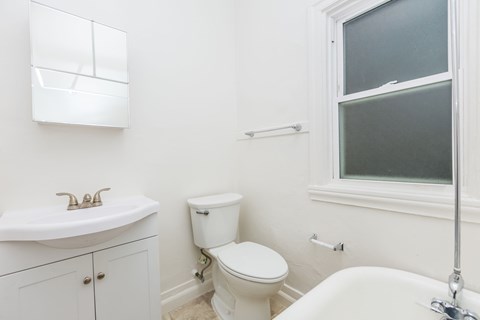 A white bathroom with a toilet, sink, and bathtub.
