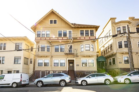 A row of houses with cars parked in front.