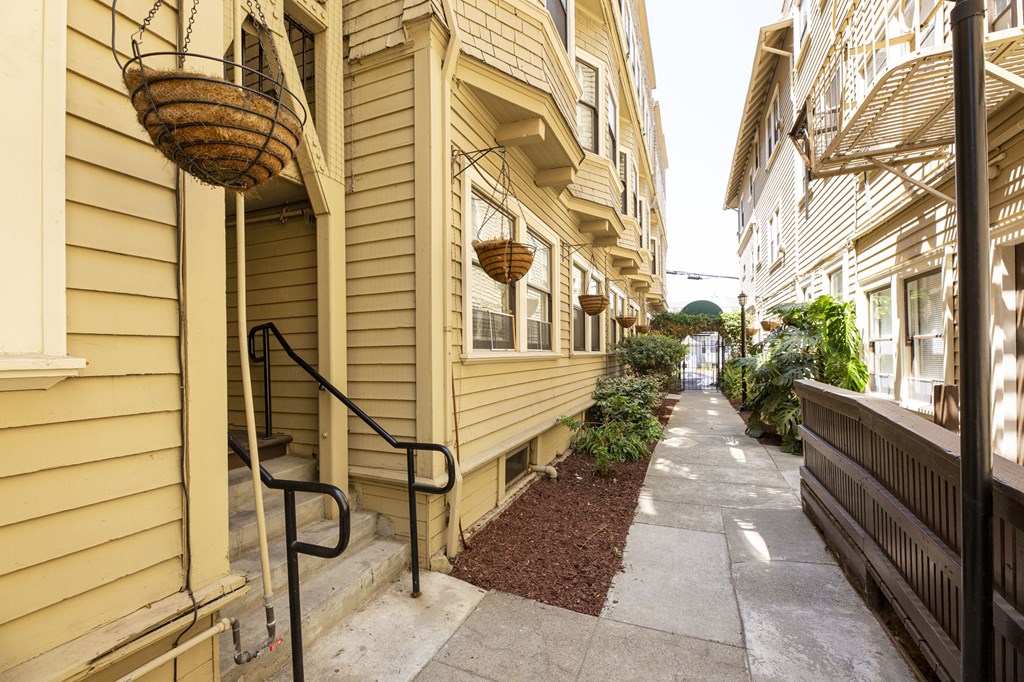 a narrow sidewalk in front of a yellow building