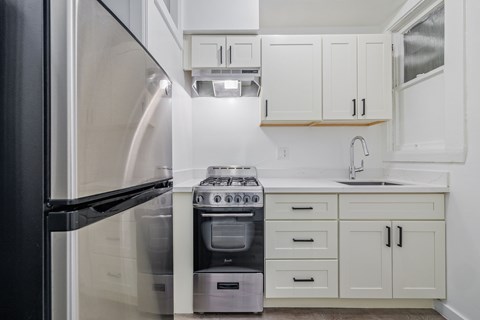 A modern kitchen with a black refrigerator and white cabinets.