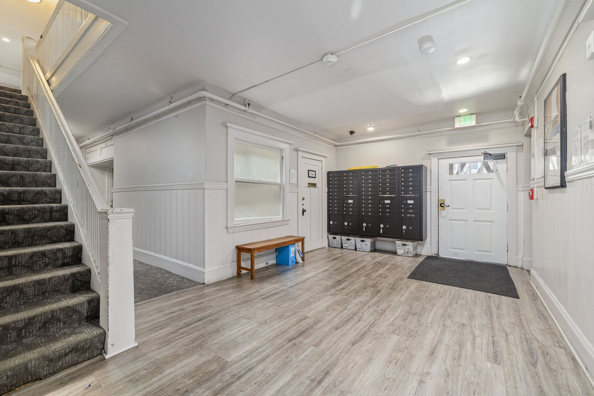 A room with a staircase on the left and a white door on the right.