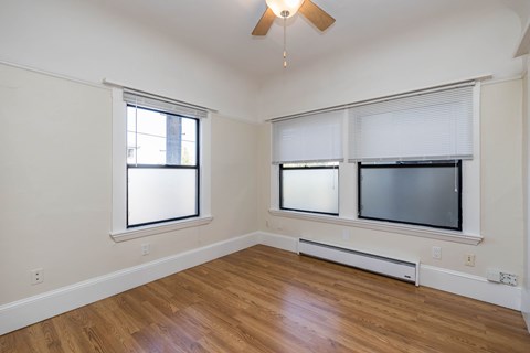 A room with a ceiling fan and a window with blinds.