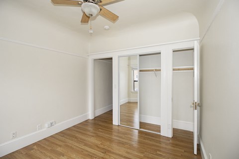 A room with a ceiling fan and a door leading to another room.