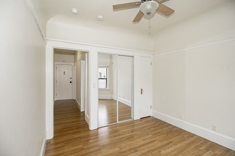 A room with a ceiling fan and wooden floors.