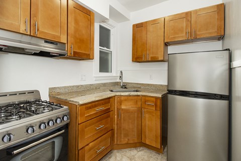 A kitchen with a stove, refrigerator, and cabinets.