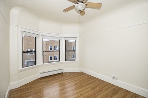 A room with a ceiling fan and wooden floors.