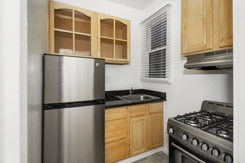 A kitchen with a stainless steel refrigerator and a stainless steel gas stove.