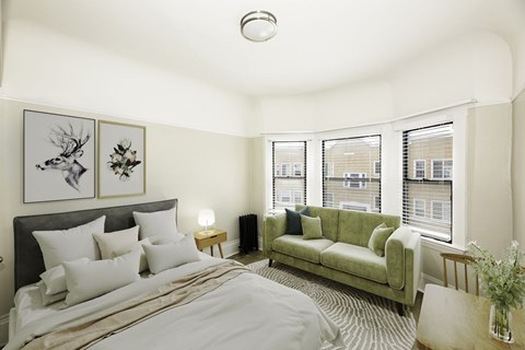 A bedroom with a large bed and a green couch.
