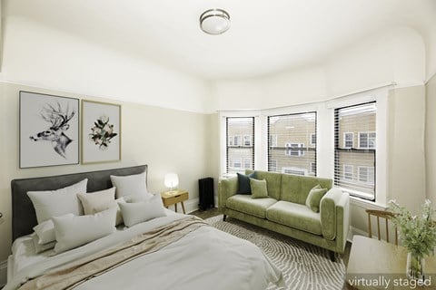 A bedroom with a bed, couch, and pictures on the wall.
