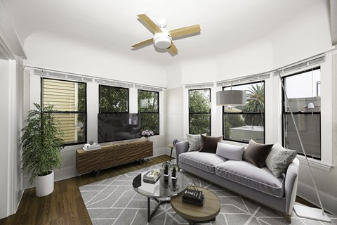 A living room with a white couch, a wooden table, and a ceiling fan.