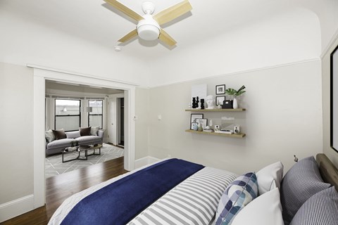 A bedroom with a bed, a couch, and a ceiling fan.