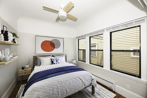 A bedroom with a bed, a ceiling fan, and a painting on the wall.