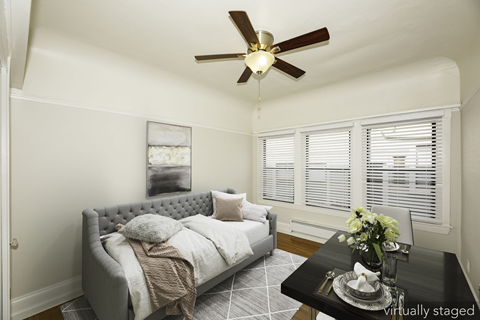 A bedroom with a grey bed and a black coffee table.