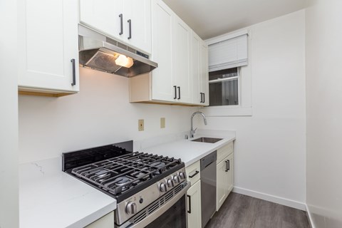 A kitchen with a stove top oven and white cabinets.