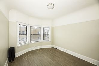 an empty room with three windows and a wood floor