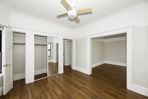 A room with a ceiling fan and wooden floors.