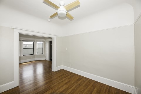 A room with a ceiling fan and wooden floors.