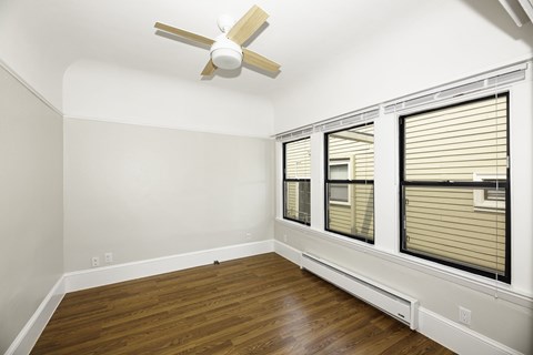 A room with a ceiling fan and two windows with blinds.