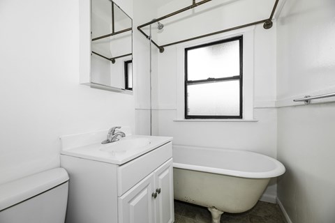 A white bathroom with a claw foot tub.